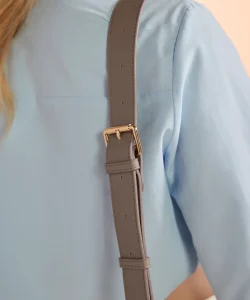 A close-up view of the golden buckle on the Athena cross-body bag used to tighten or loosen the shoulder strap.