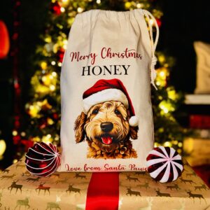 A photo of a natural coloured Christmas sack with a picture of a dog on the front with the personalised text "Merry Christmas Honey Love From Santa Paws" split above and below.