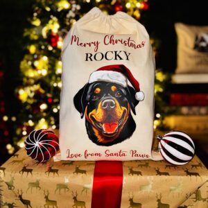 A photo of a natural coloured Christmas sack with a picture of a rottweiler dog on the front with the personalised text "Merry Christmas Rocky Love From Santa Paws" split above and below.