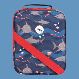 In front of a cornflower blue background: a navy kids' lunch bag with imagery of sharks and various tropical fish in front of waves of various shades of blue.